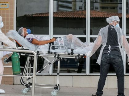 Paciente deitado em maca e respirando com ajuda de oxigênio hospitalar na entrada de unidade de saúde