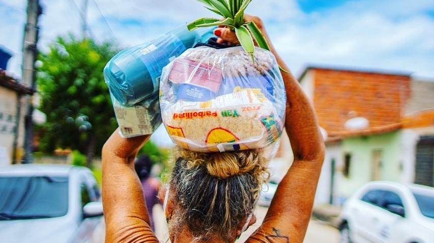Mulher carrega cesta básica no Ceará
