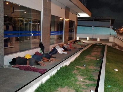 Pessoas dormindo na calçada de agência da caixa em Fortaleza