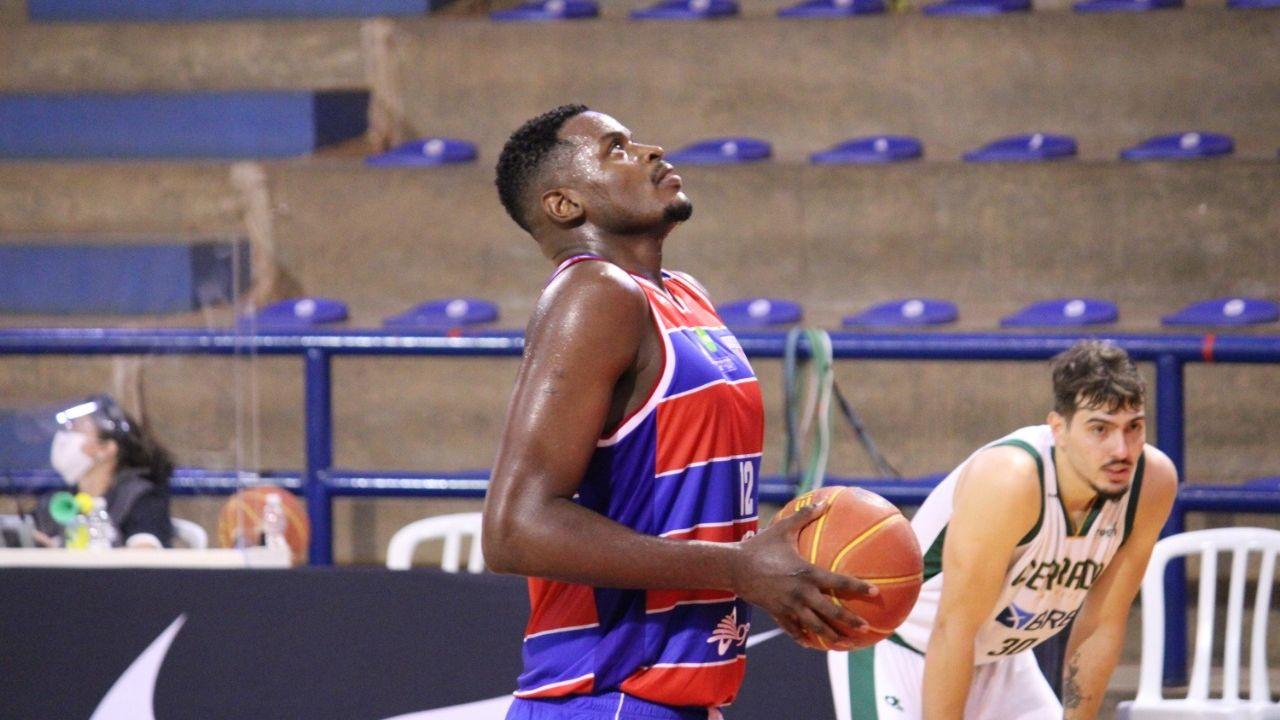 Jogador de basquete Thiago Mathias com uma bola na mão, olhando para a cesta