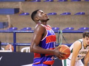Jogador de basquete Thiago Mathias com uma bola na mão, olhando para a cesta