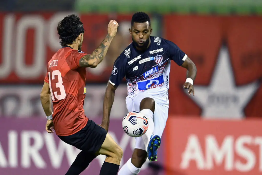 Dois jogadores disputam bola em lance aéreo durante partida de futebol