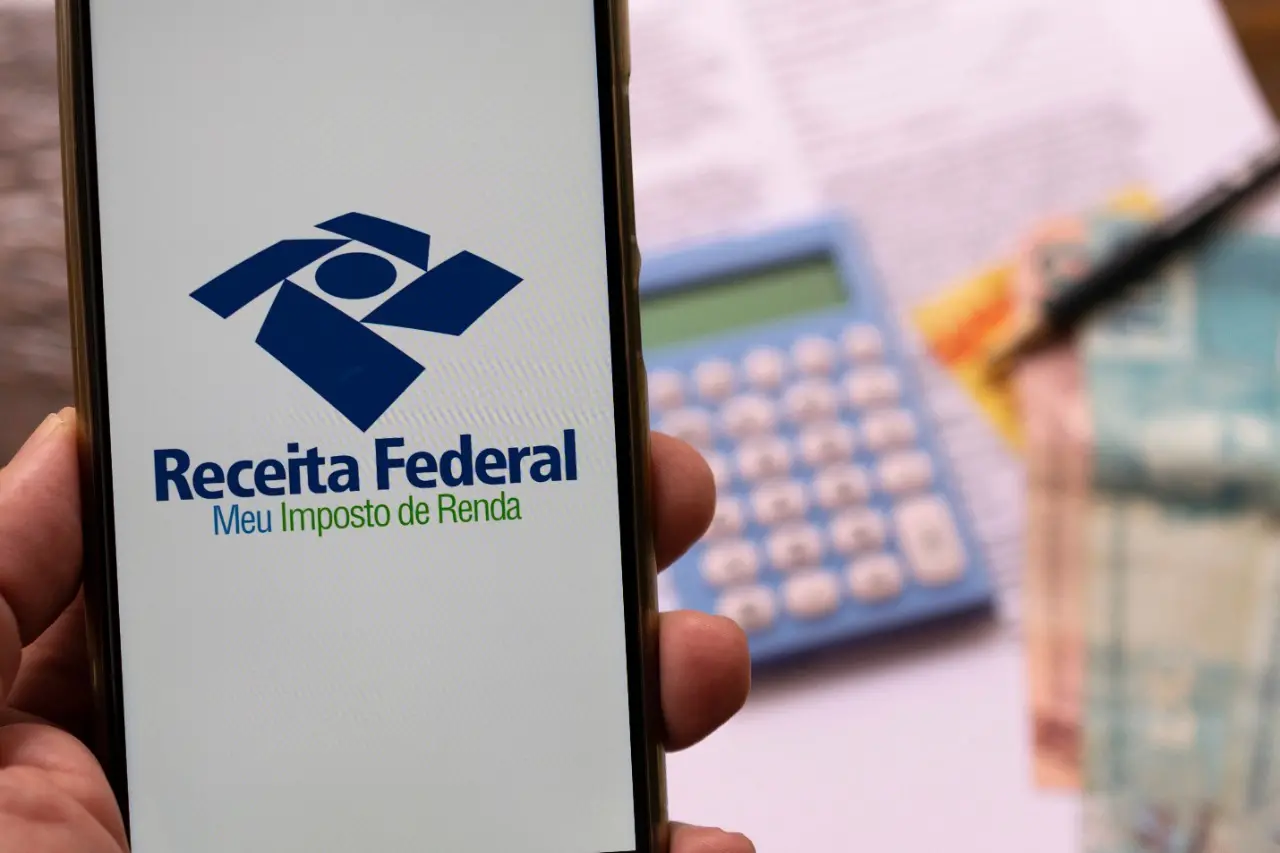 Celular em mãos com pedido de declaração de imposto de renda da Receita Federal. Foco seletivo. irpf 2021.