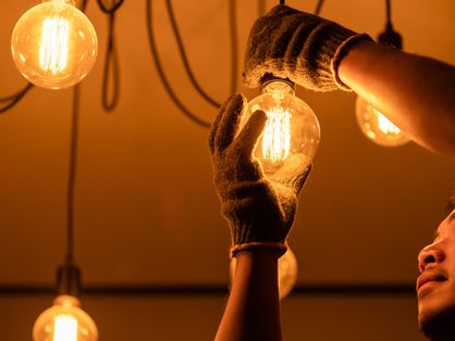 Homem troca iluminação de lâmpadas de energia elétrica