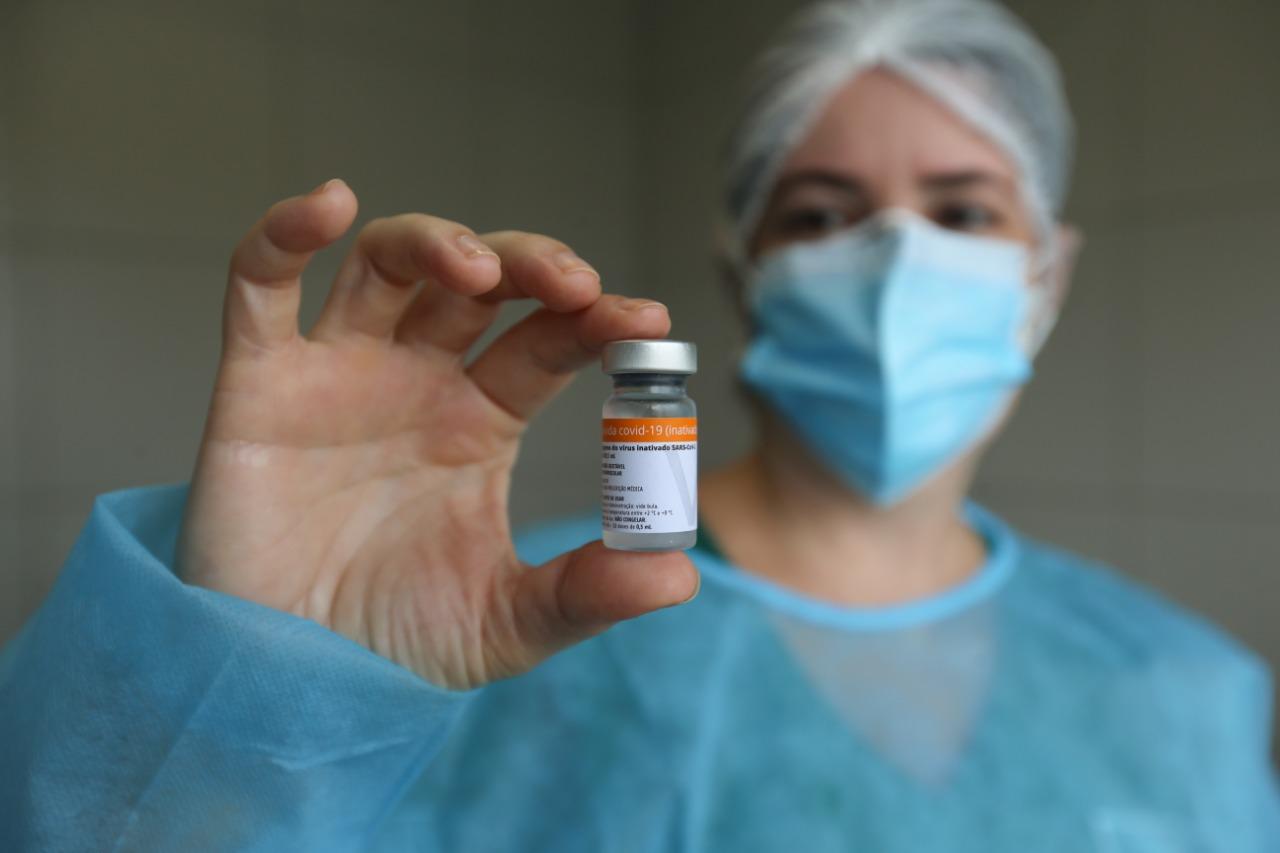 profissional da saúde exibe frasco da vacina coronavac