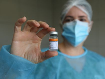 profissional da saúde exibe frasco da vacina coronavac