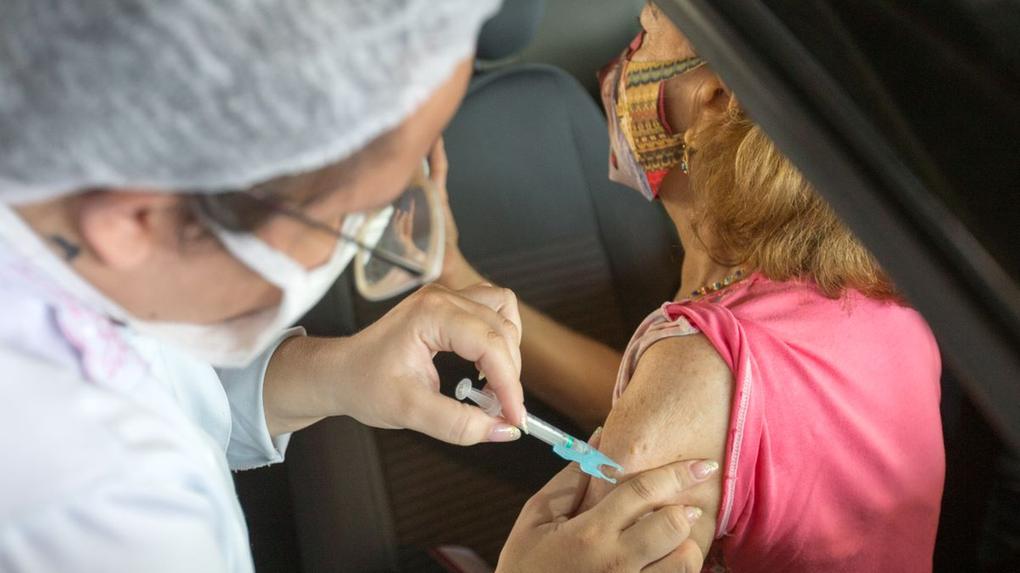 Profissional de saúde vacinando idosa contra a Covid-19 em Fortaleza