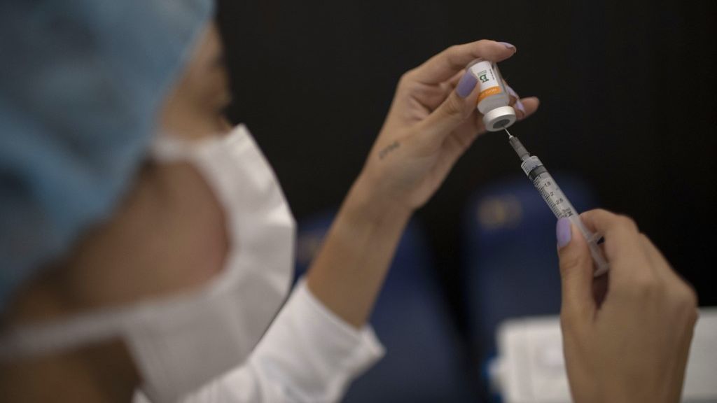 Vacina CoronaVac nas mãos de profissional da saúde