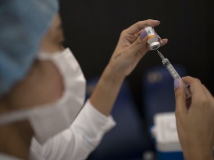 Vacina CoronaVac nas mãos de profissional da saúde