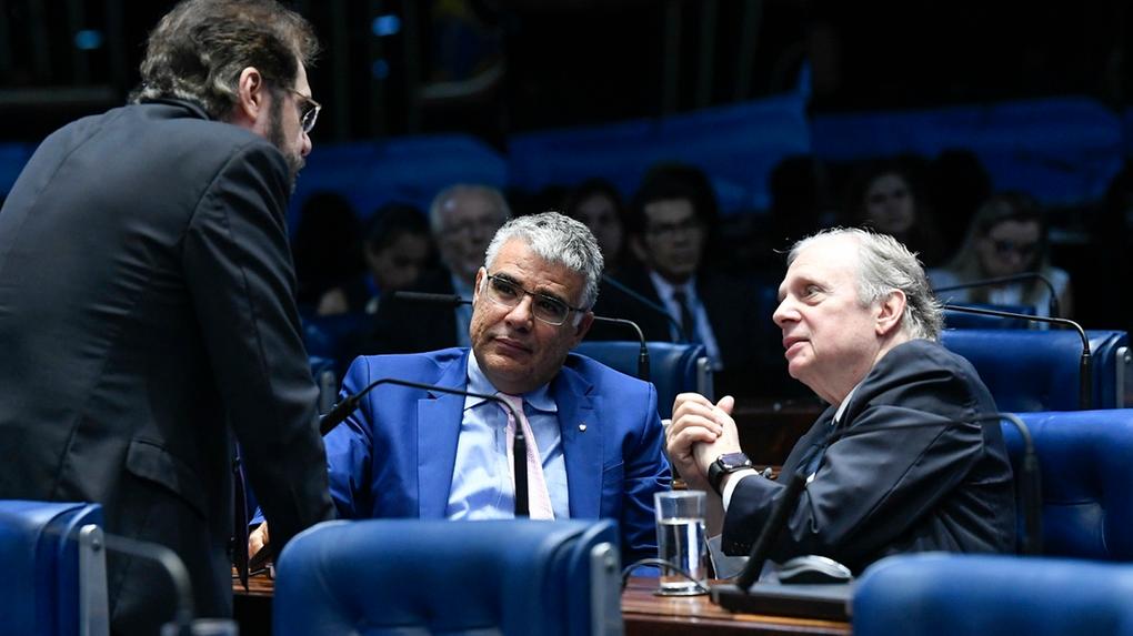 Senadores Tasso Jereissati e Eduardo Girão conversam com outro senador, que está de costas, no plenário do Senado