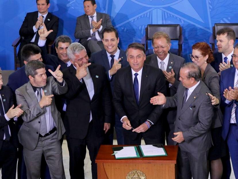 Bolsonaro assina documento ao lado de apoioadores