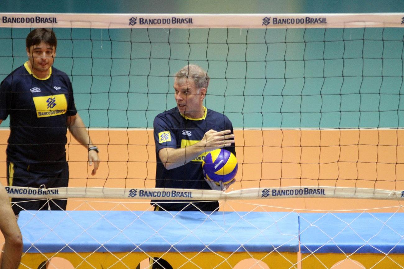 Ex-técnico de vôlei do Brasil Bernardinho atrás de uma rede de vôley segurando uma bola