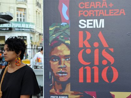 Mulher ao lado de propaganda que fala de racismo no Ceará