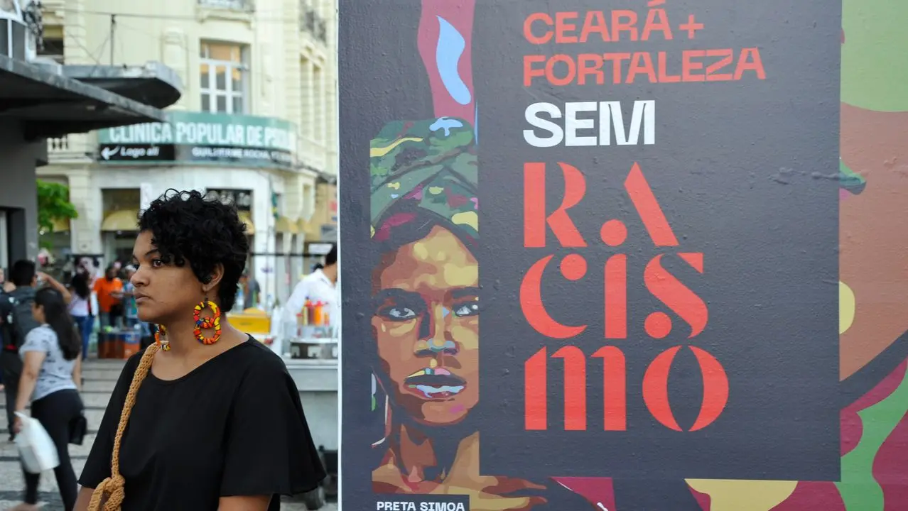 Mulher ao lado de propaganda que fala de racismo no Ceará