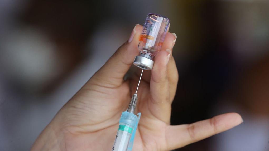 Profissional prepara seringa para aplicar vacina