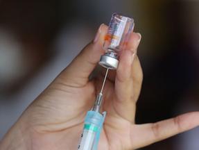 Profissional prepara seringa para aplicar vacina
