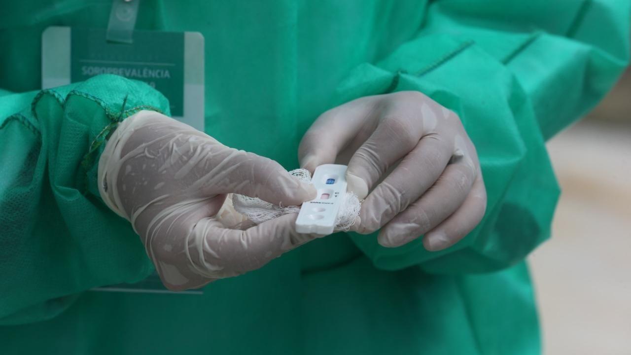 Mãos de médico com luvas segurando teste de covid-19