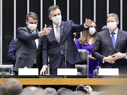 Presidente Jair Bolsonaro ao lado de Rodrigo Pacheco e Arthur Lira no Congresso. Pacheco e Bolsonaro apontam para a direita, com o presidente da República fazendo 
