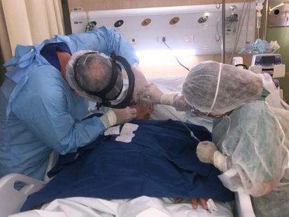 Dentistas hospitalares auxiliando paciente com Covid-19