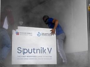 carga de vacinas Sputnik sendo empurrada por homens para dentro de caminhão