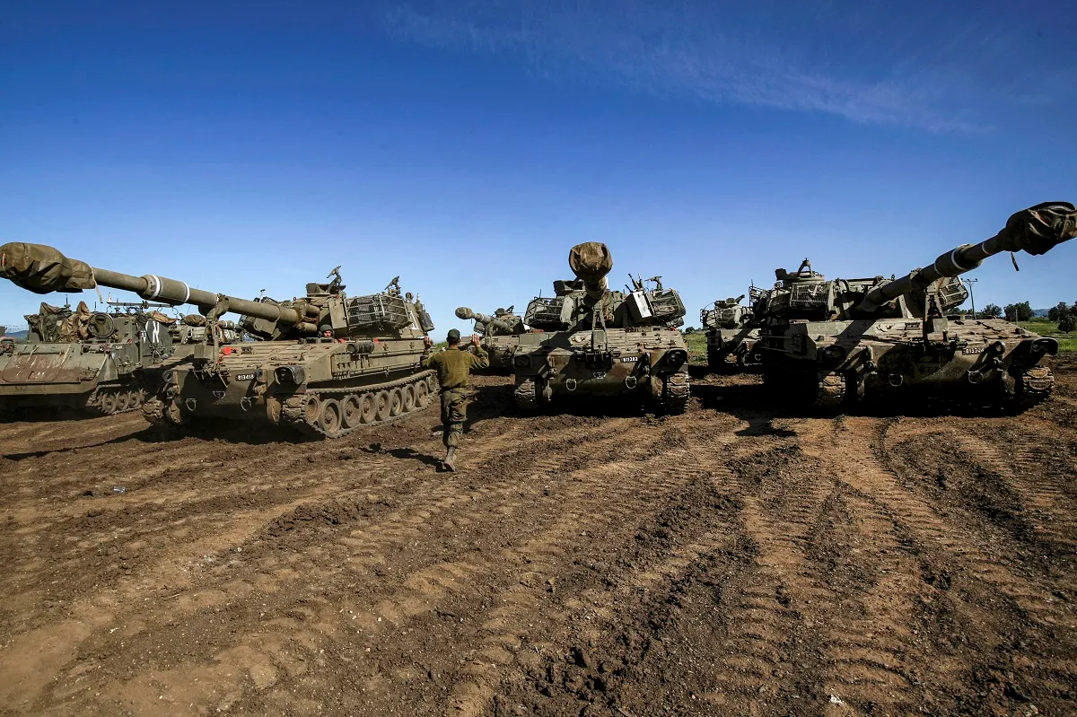 Um soldado israelense faz um gesto para os motoristas de canhões de artilharia nas colinas de Golan