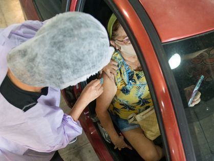 Mulher sendo vacinada dentro de carro em drive-thru