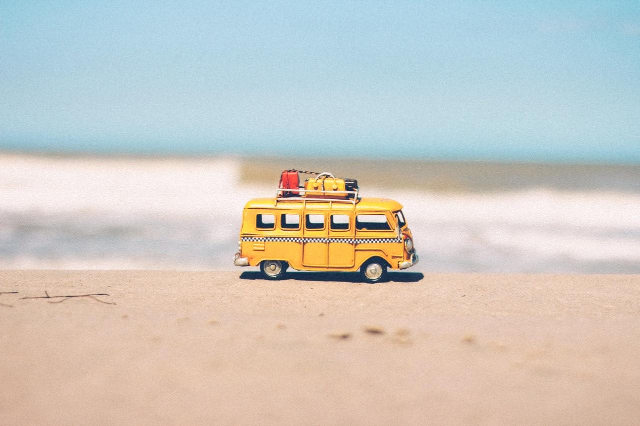 carrinho em miniatura com malas em cima e fundo de praia