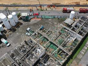 Vista aérea da destruição da fábrica da White Martins após a explosão, com cilindros de oxigênio verdes espalhados pelo chão, vidros e telhados quebrados