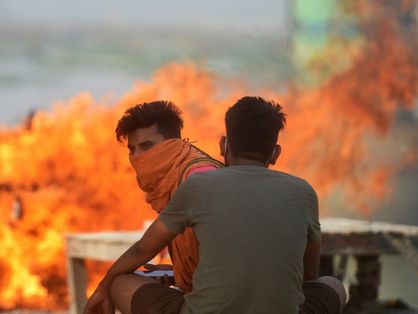 Duas pessoas durante cremação de mortos por Covid-19 na Índia