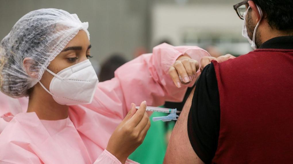 Enfermeira aplica vacina no braço de uma pessoa