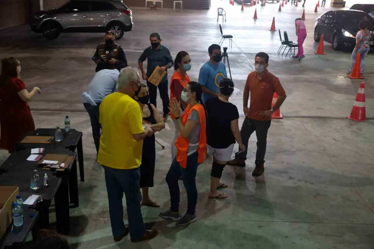 Pessoas em busca da segunda dose de vacina contra a Covid-19 no Centro de Eventos falando com profissionais da saúde