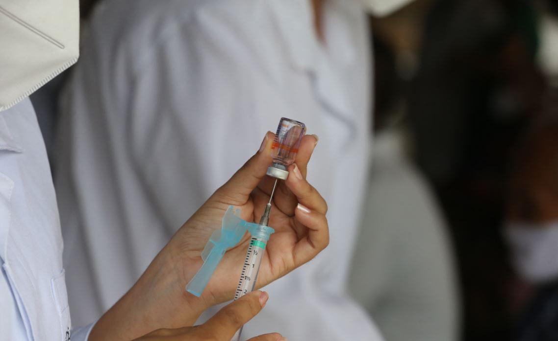 Enfermeira segurando dose de CoronaVac e seringa