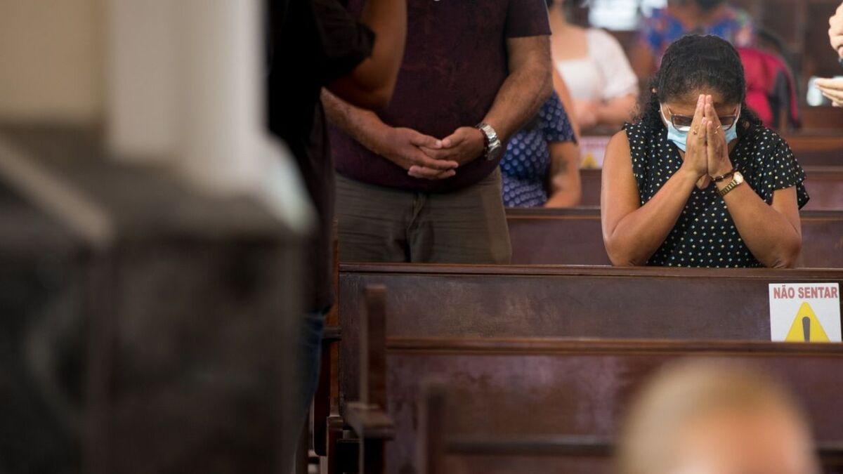 Fiéis ajoelhados durante a missa. Reabertura de igrejas agora ocorrerá nos fins de semana