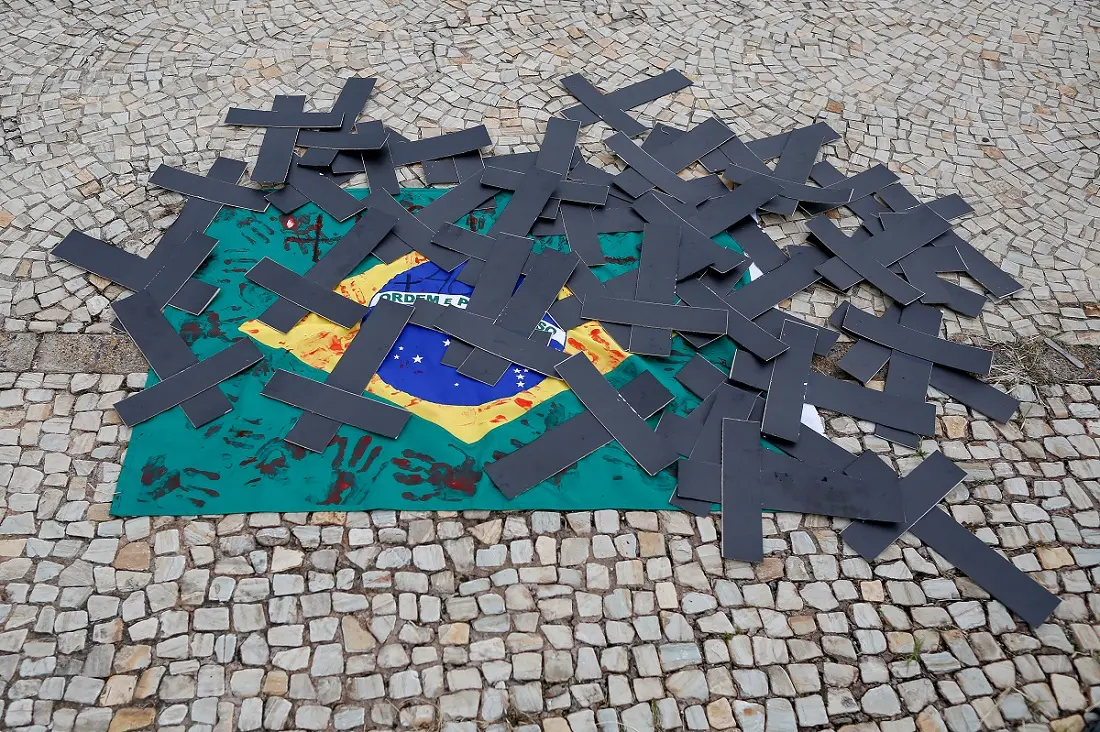 Bandeira do Brasil no chão com cruzes pretas em cima dela