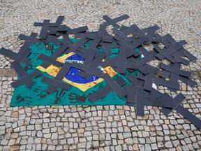 Bandeira do Brasil no chão com cruzes pretas em cima dela