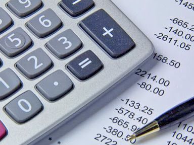 Foto ilustrativa com calculadora, extrato bancário e caneta sobre a mesa