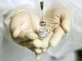 Profissional segura o frasco da vacina na palma da mão