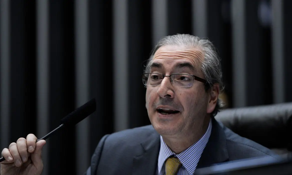 Cunha com semblante risosonho falando ao microfone