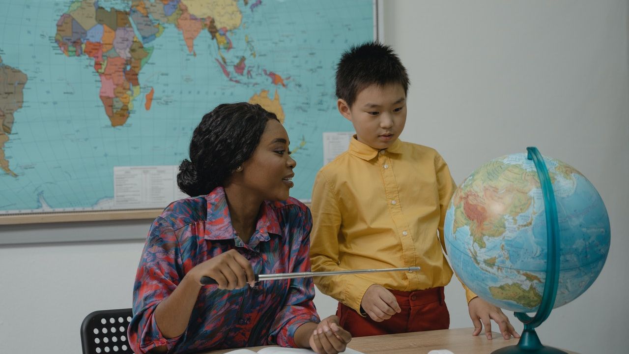 Mulher negra professora com aluno asiático