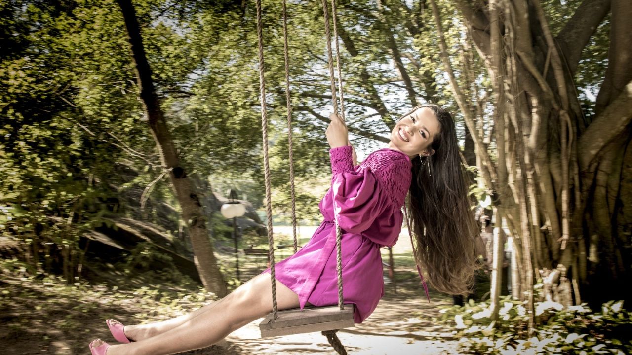Juliette Freire, participante do BBB21 e ganhadora da edição, sentada em um balanço em um parque com vestido rosa