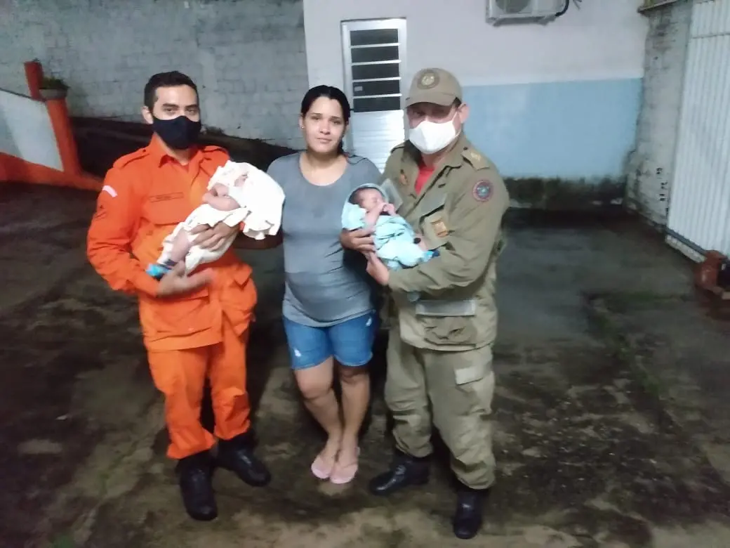 Foto de agentes do corpo de bombeiros com duas crianças e mãe resgatados de casa alagada