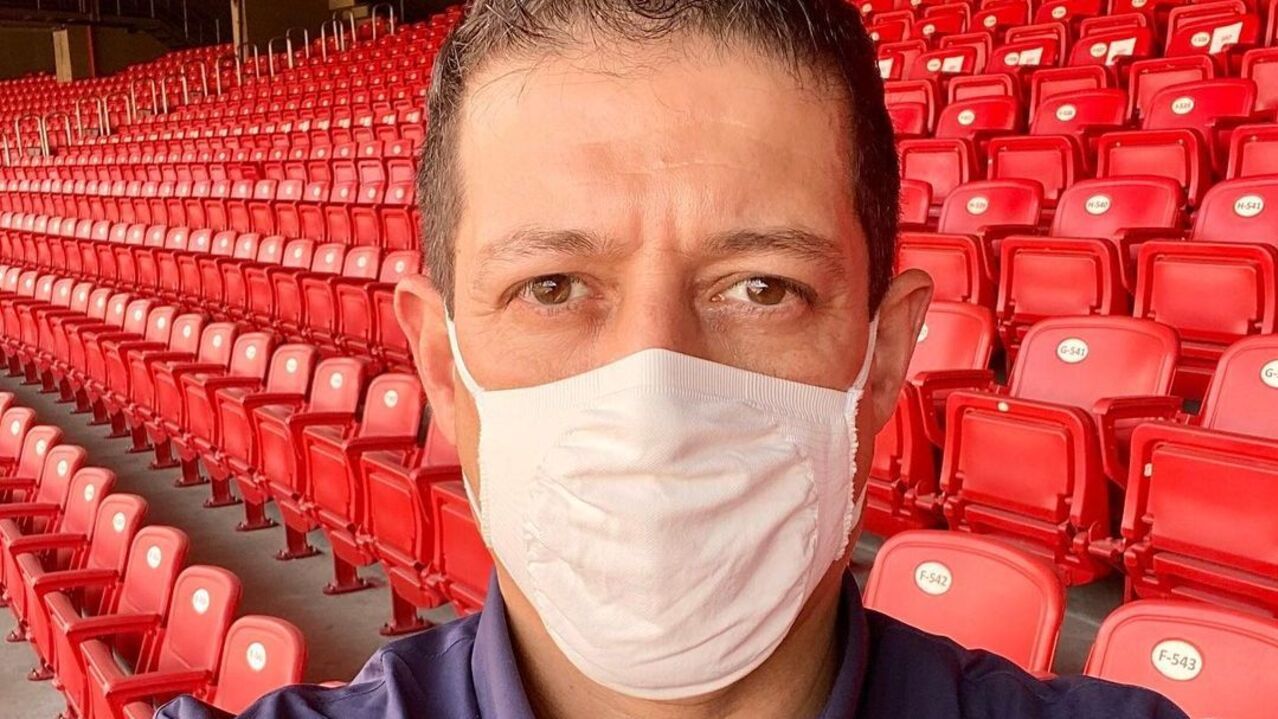 Foto do jornalista Fernando Caetano usando máscara em estádio vazio. Ele morreu neste domingo (09).