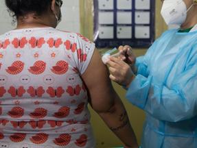 Mulher sendo vacinada contra a gripe por enfermeira