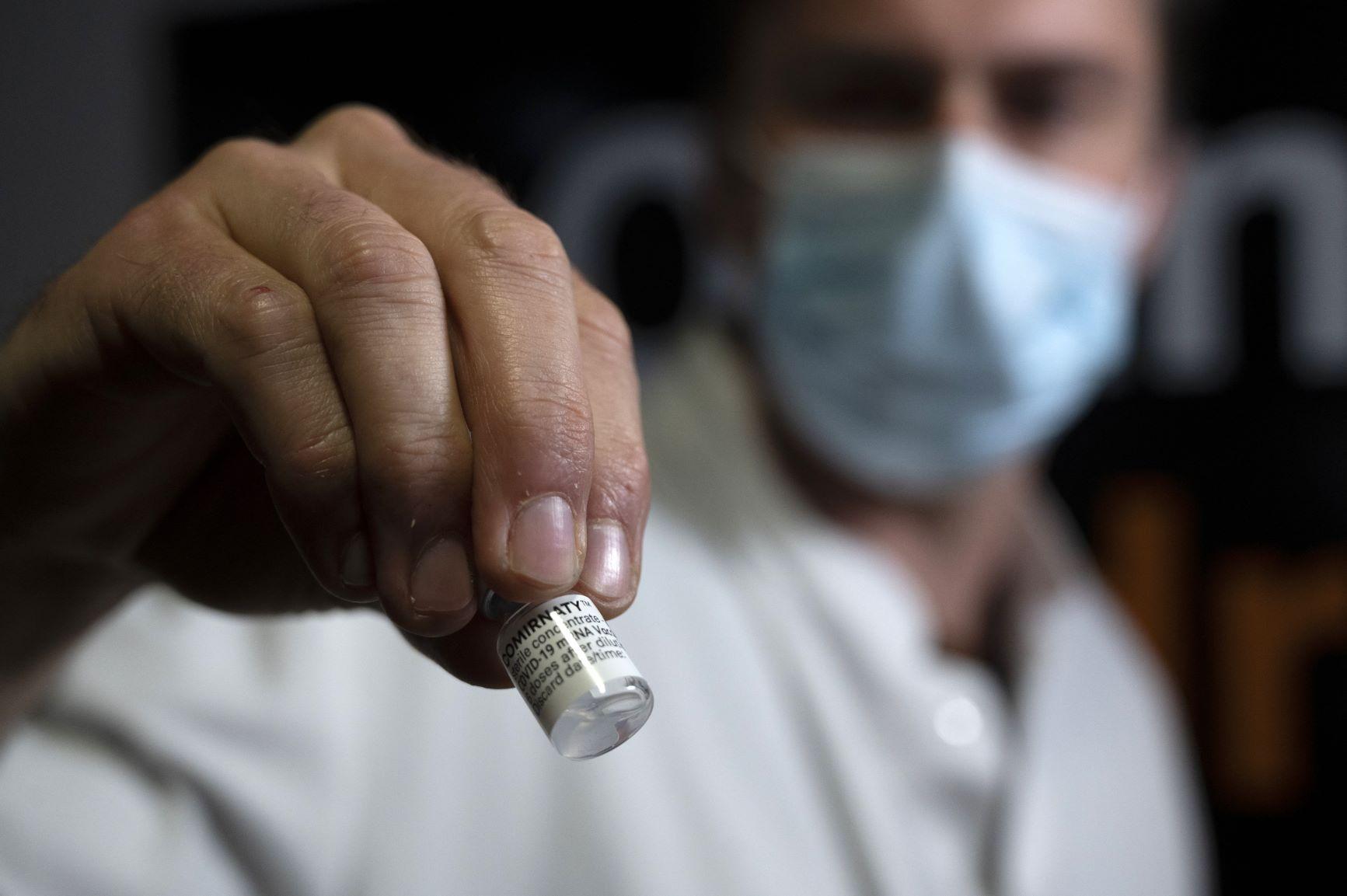 homem segura frasco com doses de vacina