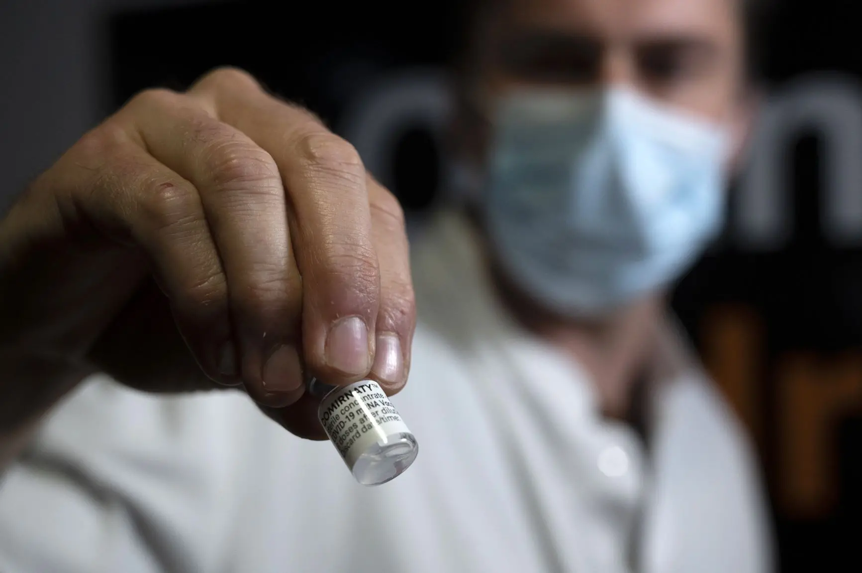 homem segura frasco com doses de vacina