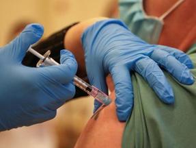 Profissional usa luvas azuis para aplicar vacina em uma pessoa