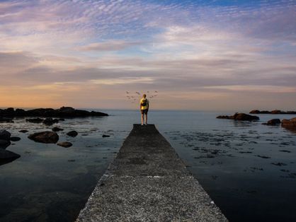 Homem em final de ponte olhando para o horizonte