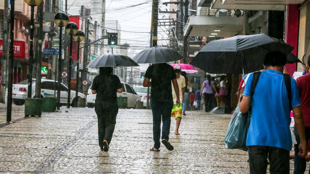 Pessoas passeiam usando guarda-chuva