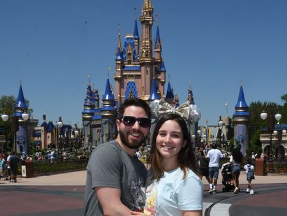 Foto de casal posando em frente de castelo da Disney