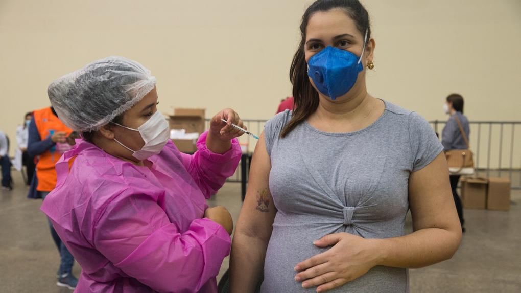 Grávida sendo vacinada contra a covid-19 por profissional da saúde no centro de eventos do ceará